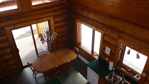 A wooden cabin interior with a dining table, chairs, a sink, and a window. - Loons Nest - Cozy, secluded 4 bedroom log cabin in the heart of the wilderness! (Tyaughton Lake)