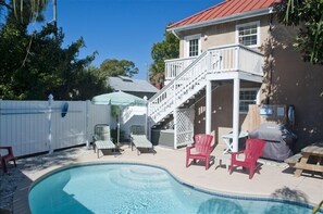 Ein Garten mit Schwimmbad, einer überdachten Terrasse und einem zweistöckigen Haus mit rotem Dach.