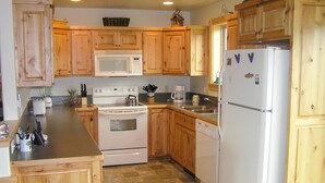 Cocina con gabinetes de madera, microondas, estufa, lavavajillas y refrigerador.