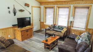Una sala de estar con televisor, muebles de madera y una ventana con persianas.