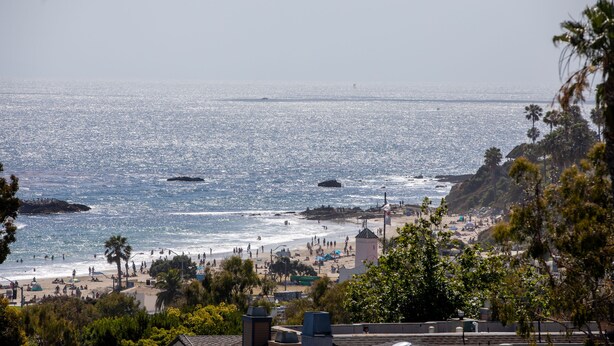 Vista costera con playa, palmeras y un faro.