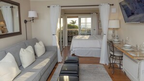 Una habitación de hotel con cama, sofá, mesa de comedor y balcón con vistas.
