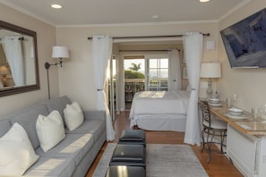 Une chambre d’hôtel avec un lit, un canapé, une table à manger et un balcon avec vue.