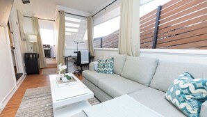 Una sala moderna con un sofá, una mesa de centro y vistas a una terraza de madera.