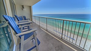 A balcony with blue chairs and a view of the ocean.