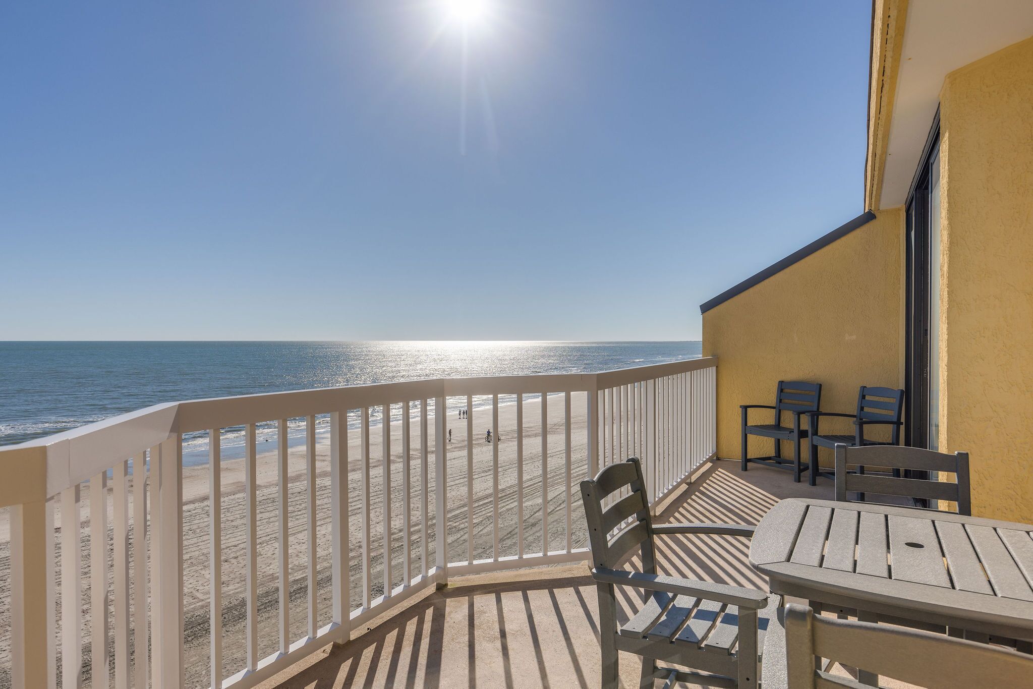 A balcony with a view of the beach and ocean.