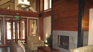A lobby with a fireplace, seating area, and an exit sign. - 5th-Floor With Beautiful Views • Full Kitchen • Elegant New Italian Sleeper Sofa (Winter Park)