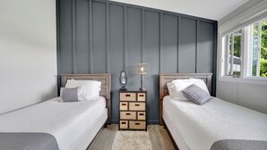 A bedroom with two beds, a nightstand with a lamp, and a window with a view of greenery. - Beautiful and modern 3 bedroom, 1 bath Duplex.  Sleeps 6 (Chaffee)