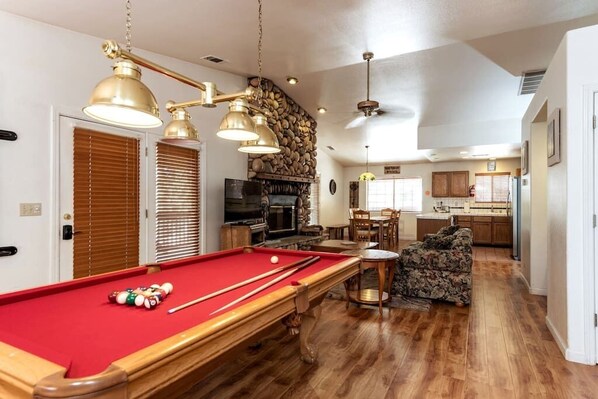 A pool table with balls, a sofa, and a dining area with chairs and a table.