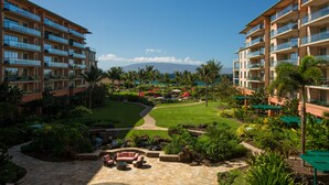 Un complexe hôtelier comprenant des bâtiments à plusieurs étages, des espaces de détente en plein air et un jardin bien entretenu, avec un sentier menant à une zone abritant une piscine.