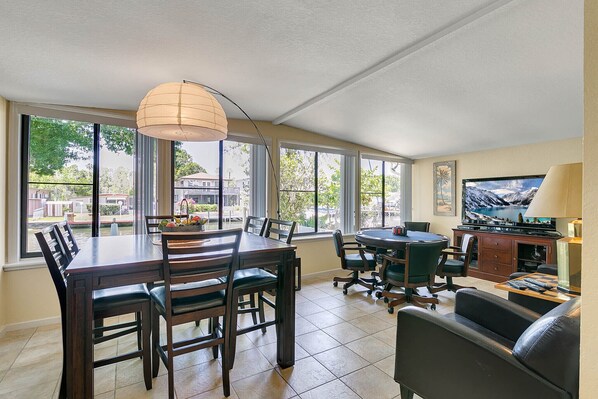 A spacious dining area with a large table and chairs, a television, and a comfortable seating area with a sofa and a lamp. - HAVE IT ALL with floating dock, commercial icemaker and deepest canal in town! (Crystal River)