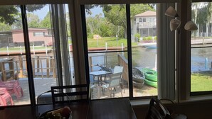 A room with large windows overlooking a dock area with boats and a grassy area.