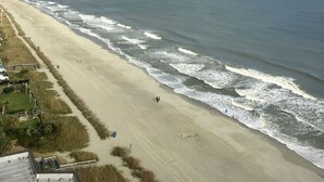 Una playa con un arcoíris visible, orilla arenosa y olas del océano.