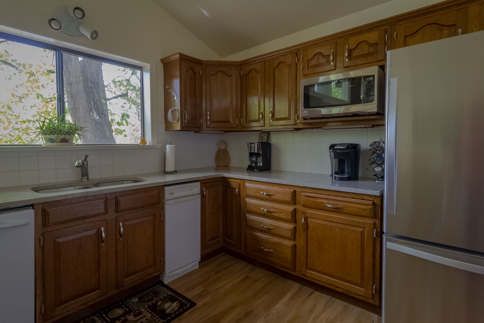 A kitchen with wooden cabinets, a stainless steel refrigerator, a microwave, a coffee maker, and a dishwasher.