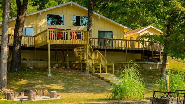 Une cabane en bois à deux étages, dotée d’une terrasse couverte et d’un escalier.