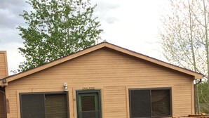Een chalet met een veranda, een groene deur en een bord waarop 'TRAIL RIDGE' staat.