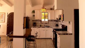 Una cocina amplia con armarios blancos, piso de baldosas y una lámpara colgante.