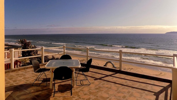 Una terraza con una mesa y sillas con vista al océano.