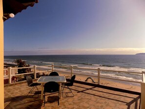 A terrace with a table and chairs overlooking the ocean. - Spacious Oceanfront home with private access to the beach in a gated community. (Tijuana)