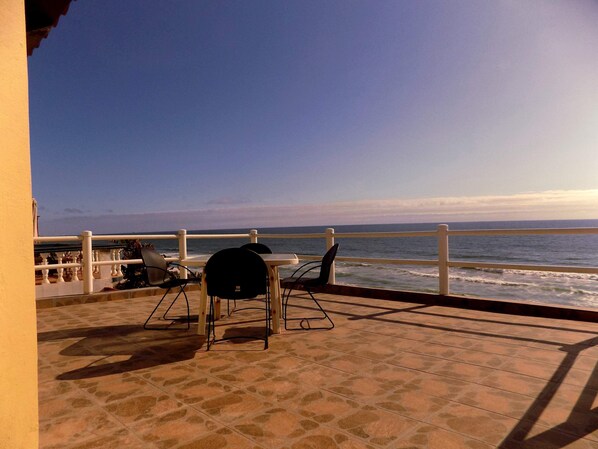 A patio with a view of the ocean, featuring a table and chairs. - Spacious Oceanfront home with private access to the beach in a gated community. (Tijuana)