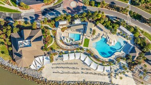Vista aérea de un complejo turístico con una piscina grande, tumbonas y una zona de playa.