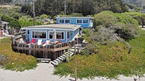 A coastal house with a deck, surrounded by vegetation and hills. - Oceanfront At Stinson - Relax And Refresh (Stinson Beach)