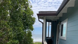 A balcony with a view of the ocean, a wooden deck, and a blue building. - Oceanfront At Stinson - Relax And Refresh (Stinson Beach)