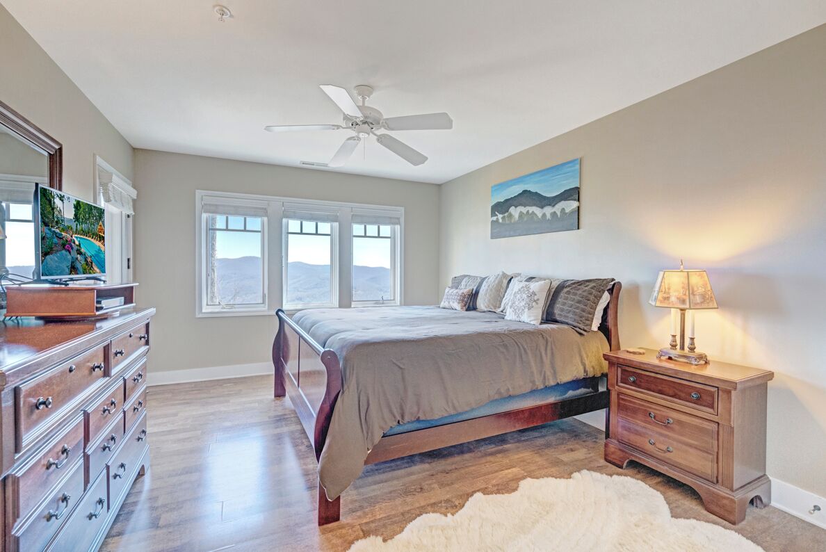 Quarto com cama, cômoda, mesa de cabeceira e ventilador de teto.