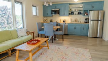 Een moderne keuken met blauwe kastjes, een roestvrijstalen koelkast en een eethoek met gestreepte stoelen.