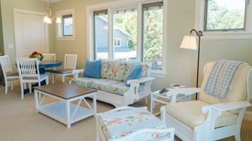 A room with a sofa, chairs, a small table, and a floor lamp.