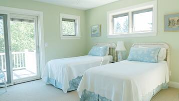 A room with two beds, a ceiling fan, and a view of the outdoors.