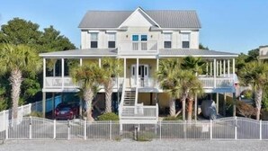 A two-story house with a balcony, a covered porch, and a fenced driveway. - South of 30A, Pet friendly home w/Heated Pool, Golf cart or walk to beach (Santa Rosa Beach)