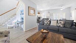 A spacious living area with a staircase, a gray sofa set, and a wooden coffee table. - South of 30A, Pet friendly home w/Heated Pool, Golf cart or walk to beach (Santa Rosa Beach)