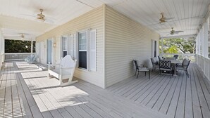 A covered porch with a white exterior, a dining table with chairs, and ceiling fans. - South of 30A, Pet friendly home w/Heated Pool, Golf cart or walk to beach (Santa Rosa Beach)
