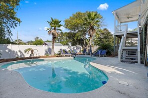 A swimming pool with lounge chairs and palm trees.