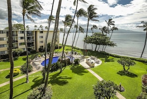 Um resort com piscina, palmeiras e vista para o oceano.