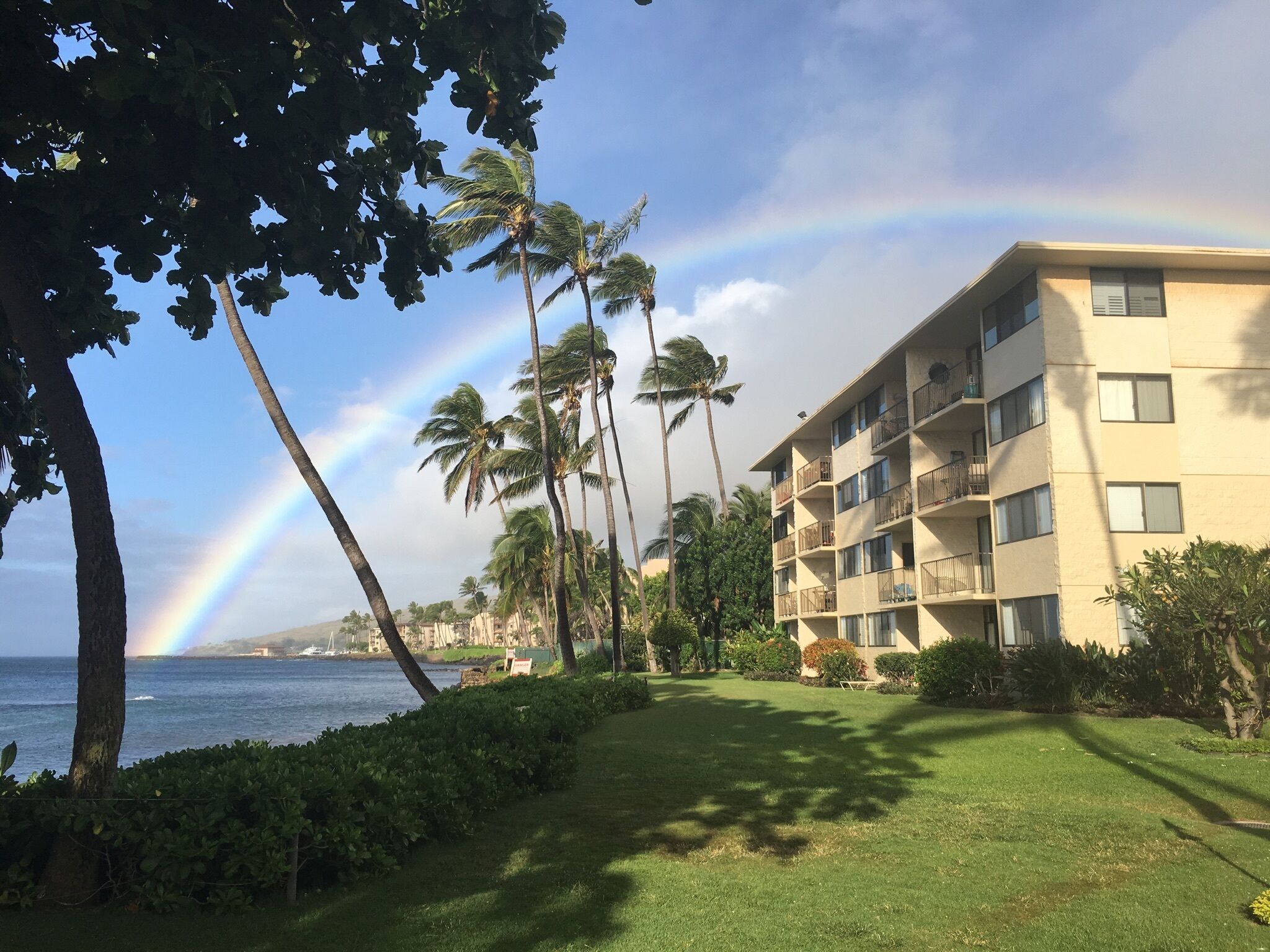A beachfront hotel with a view of the ocean and a rainbow.