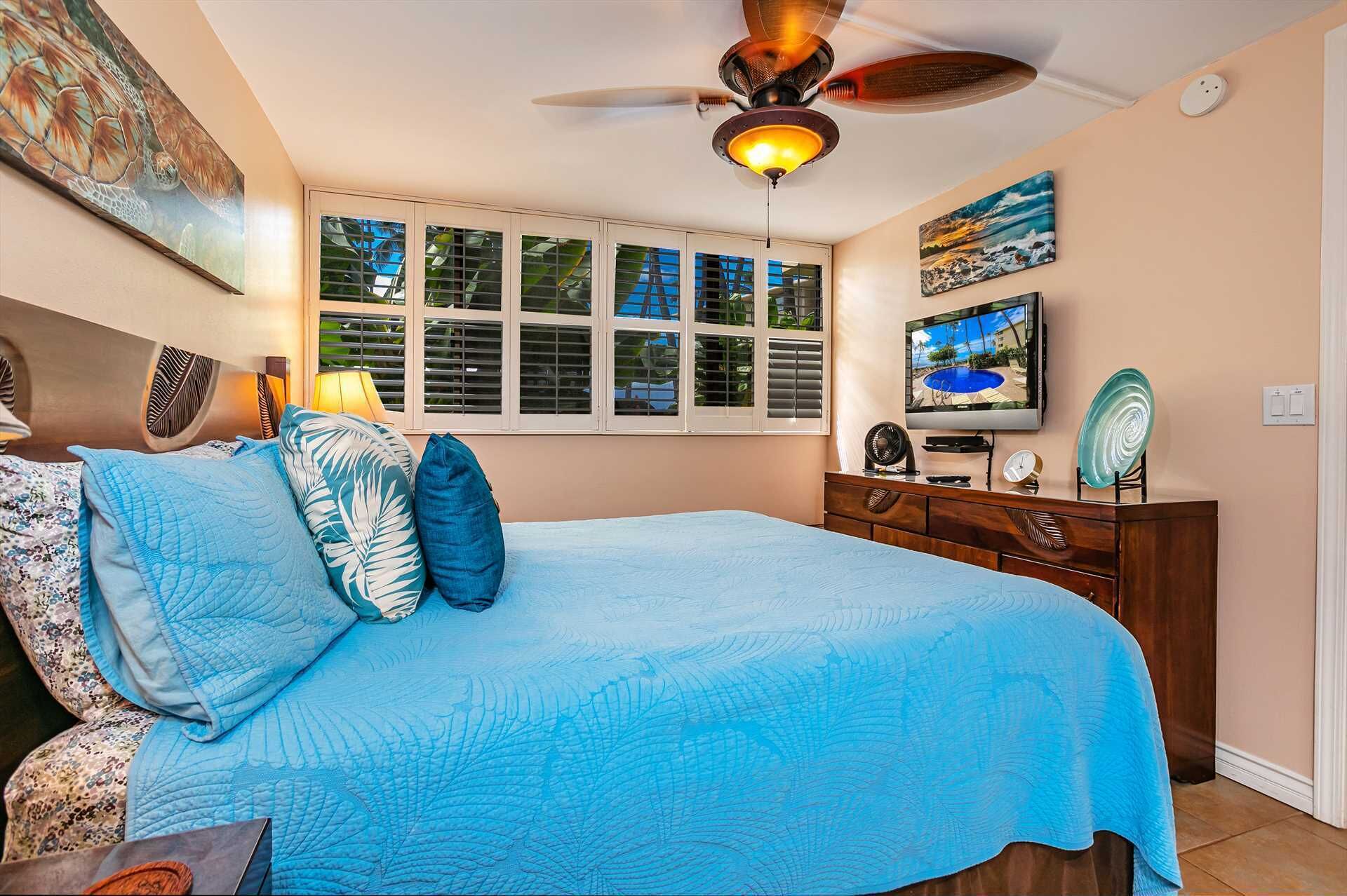 A bedroom with a bed, a ceiling fan, a TV, and a window with blinds.