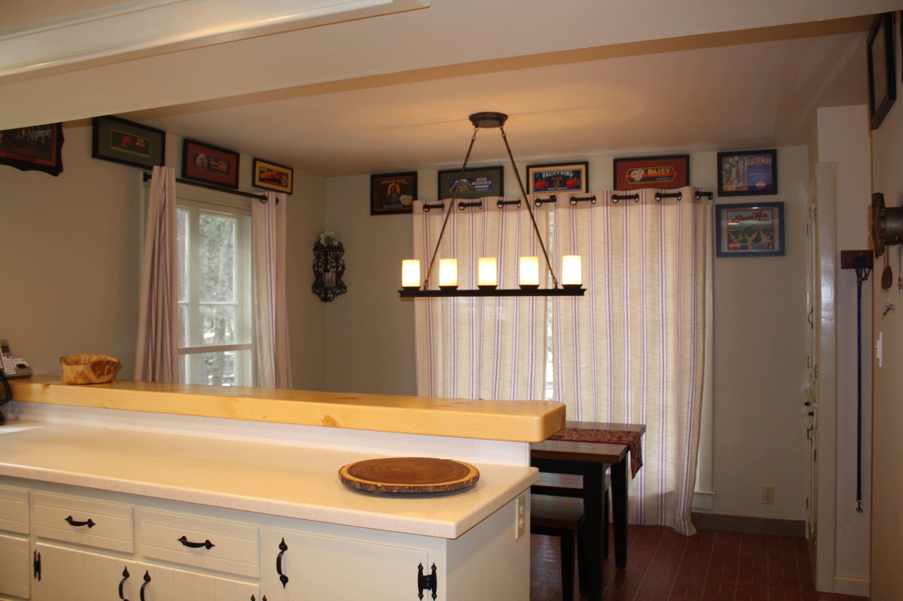 Una cocina con mostrador de madera, una lámpara colgante y un ventanal con cortinas.