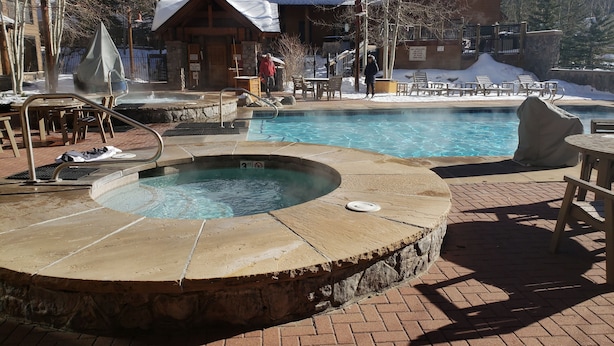 A pool area with a hot tub, lounge chairs, and a wooden deck. - New 3BR/3BA & Loft, Private Hot Tub, Heated Pool, Views, Walk/Bus to River Run (Keystone)