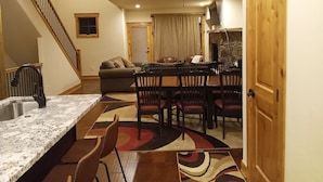 A modern kitchen with granite countertops, a dining area with a patterned rug, and a cozy living space with a sofa and a fireplace. - New 3BR/3BA & Loft, Private Hot Tub, Heated Pool, Views, Walk/Bus to River Run (Keystone)