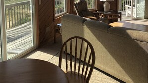 Een houten interieur met grote ramen, een comfortabele zithoek en uitzicht op het strand.
