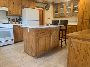 A kitchen with wooden cabinets, a white refrigerator, a stove, and a sink.