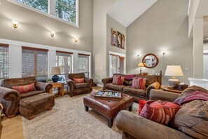 A spacious living room with leather sofas, a coffee table, and a fireplace.