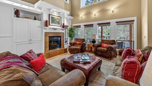 A living room with a fireplace, multiple seating options, and large windows. - Bend Getaway in RiverWild-Walk to Deschutes River and Old Mill District (Bend)