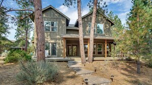 A two-story house with a large front porch, surrounded by tall pine trees and a dry grassy yard. - Bend Getaway in RiverWild-Walk to Deschutes River and Old Mill District (Bend)