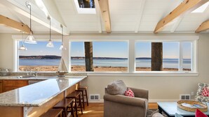 A kitchen with a large island, bar stools, and a view of the beach.