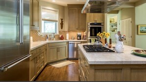 A modern kitchen with stainless steel appliances, wooden cabinets, and a central island. - Renovated, refined, immaculate single-story mountain home 2 miles south of Baldy (Hailey)