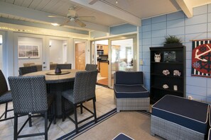 A dining area with a round table and chairs, a ceiling fan, and a kitchen visible through an open door.