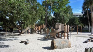 A playground with sand, wooden structures, and trees. - SeaPines, 31 Lighthouse, Pets OK, Walk to the Beach Club, Golf View, Updated (Hilton Head Island)